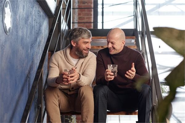 Older gay men chatting and smiling together indoors
